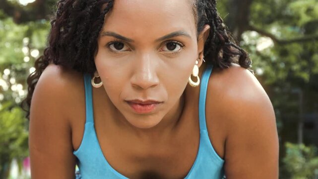 Close-up portrait of a black woman with a focused and determined look during an outdoor workout in a park. Concept of concentration, mental strength, discipline, performance and healthy lifestyle.