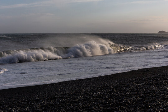 Dangerous sneaker waves crashing on Reynisfjara Black Sand Beach at sunset, Iceland
