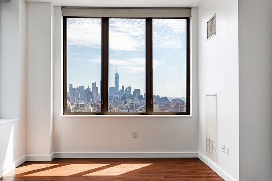 Empty apartment interior with large window and New York City skyline view