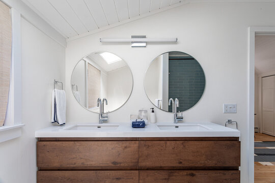 Modern bathroom interior with double sink vanity and round mirrors