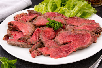 Tranches de r&ocirc;ti de b&oelig;uf saignant servies sur assiette blanche
