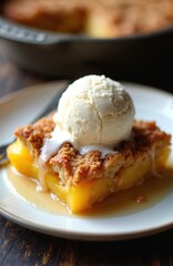 Close-up peach cobbler slice with vanilla ice cream scoop. Warm fruit dessert, baked crumble topping, sweet syrup pool. Delicious homemade treat on white plate.