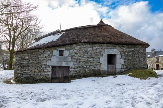 Traditional palloza stone house with snowy thatched roof in o cebreiro
