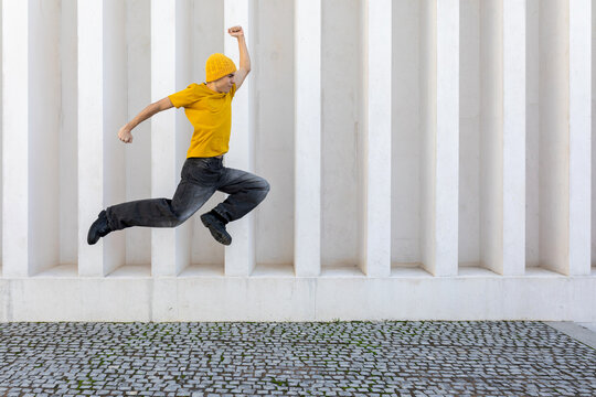 Student jumping against modern architectural background