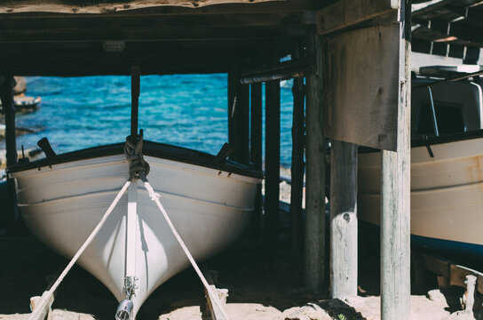 Small boat docked under a rustic wooden shelter