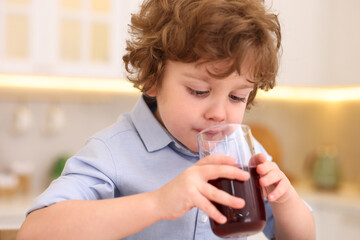 Little boy drinking fresh pomegranate juice at home