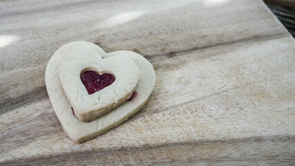 Heart shaped cookies with jam filling on wooden surface