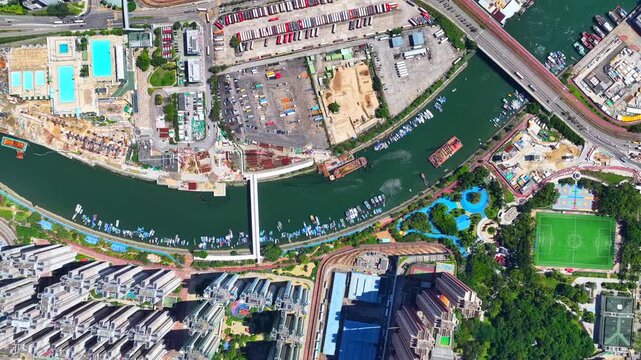 Aerial skyview of Tuen Mun subway extension project in Hong Kong, featuring elevated railway construction along Tuen Mun River and road, new station development and temporary work platforms