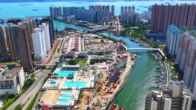 Aerial skyview of Tuen Mun subway extension project in Hong Kong, featuring elevated railway construction along Tuen Mun River and road, new station development and temporary work platforms