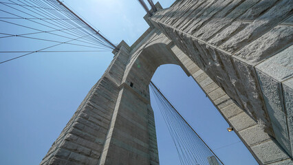 Fototapeta premium Brooklyn Bridge stone pillars captured from below highlighting structural details and grandeur
