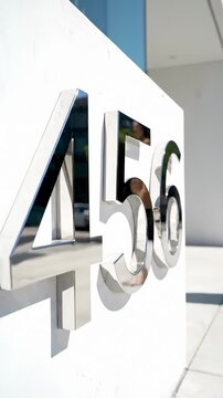 Close Up of Chrome Building Address Numbers 456 Mounted on White Exterior Wall