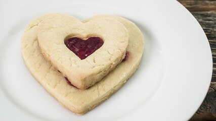 Heart cookies with a red jam filling on a white plate