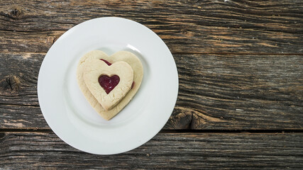 Heart shaped cookies with jam filling on rustic wood