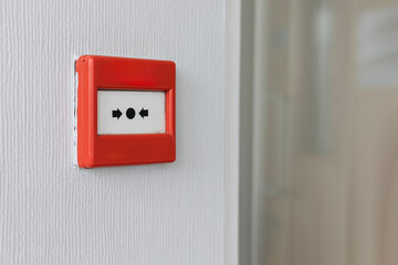 Emergency red fire alarm break glass call point mounted on white office wall