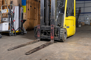 Forklift truck forks and rubber tyres parked on a storage warehouse floor © Tosh Lubek