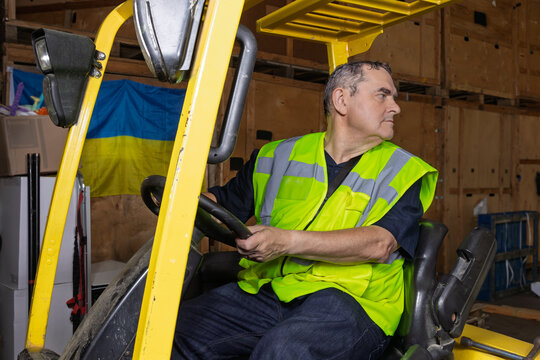Warehouse worker reversing forklift truck while looking behind