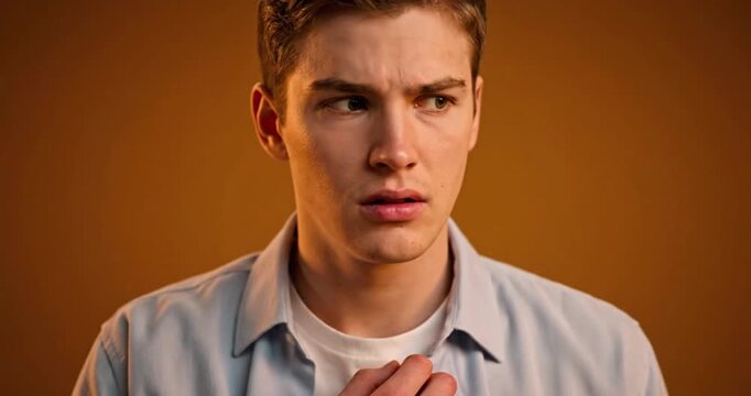 Anxious Young Man Expressing Inner Tension on Warm Studio Background
