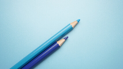 Two blue pencils are on a blue background