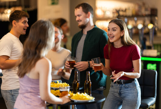 Group of friends fans having fun chatting and drinking beer in pub