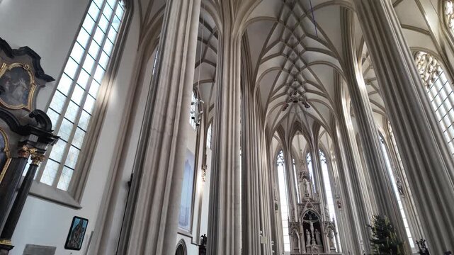 Slow motion interior view of St. James Church in Brno with soaring Gothic vaults and stained glass light