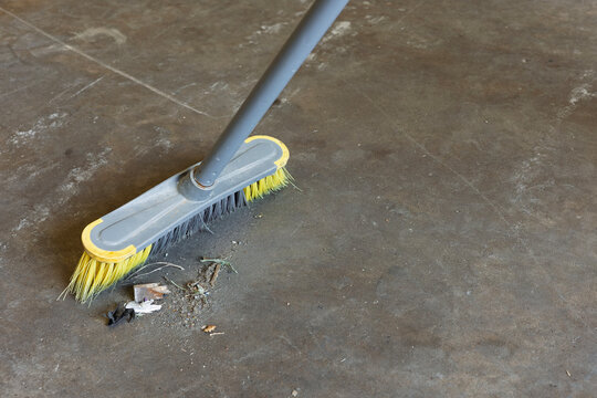 Industrial Broom Sweeping Debris on Concrete Warehouse Floor