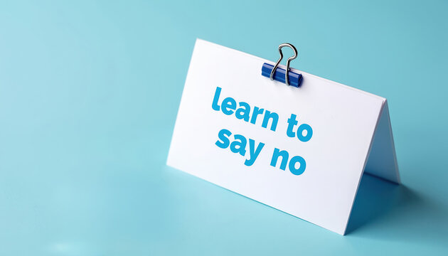 Card with phrase Learn to say no clipped with blue binder clip. Simple clean studio shot. Concept of setting boundaries and self care. Work life balance.