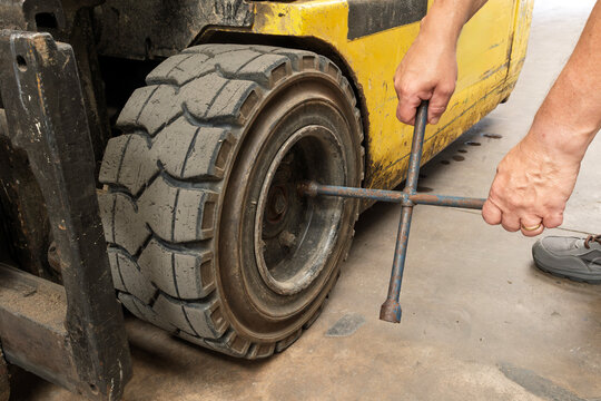 Warehouse Worker Changing Forklift Tyre Using Wrench