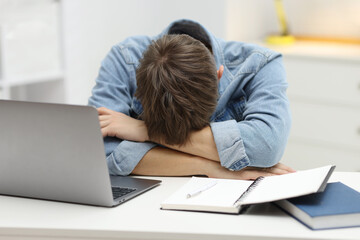 Work fatigue. Overwhelmed businessman suffering at table in office