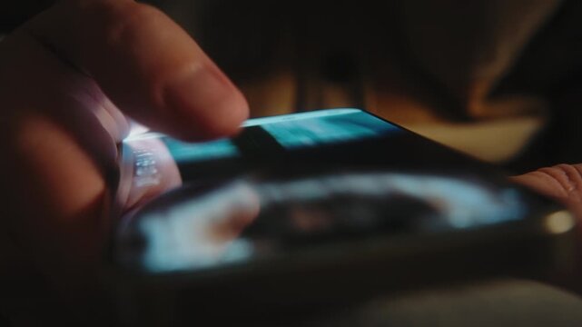 Close-up male hand in casual jacket scrolling social media feed on smartphone at night. Swipe motion blur on phone screen. Evening online browsing, digital lifestyle, content consumption, technology