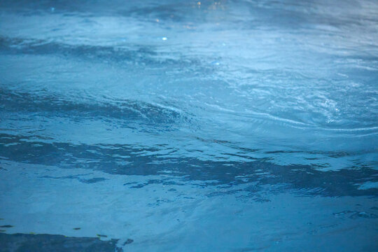 Pool at nighttime with lounger and underwater bar pool seating 