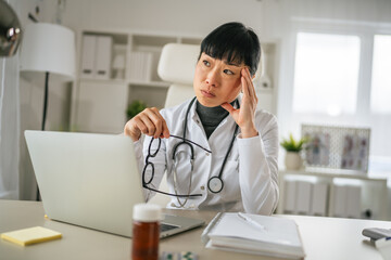 Fototapeta na wymiar Female doctor experiencing headache and stress at work