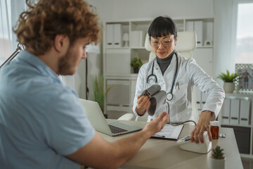 Obraz premium Doctor measuring young patient blood pressure during medical checkup