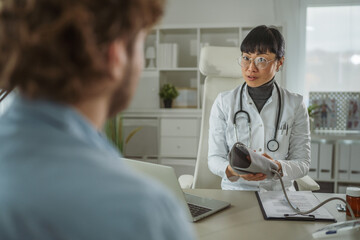 Obraz premium Female doctor explaining blood pressure monitor to male patient