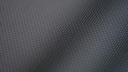 Focused close-up of a dark, textured surface reveals a stunning array of small, geometric shapes. The interplay of light and shadow enhances the visual allure, inviting touch and exploration.