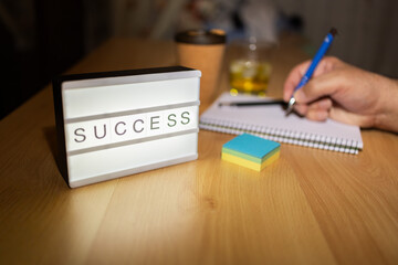 Light box showing success message and person writing goals