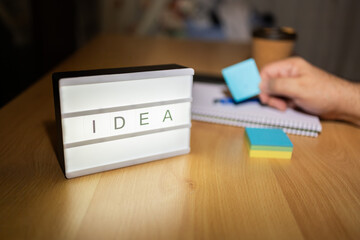 Lightbox displaying idea word on desk with sticky notes