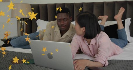 Watching couple lying on bed wearing cream, pink tops, using laptop near green phone, gold stars