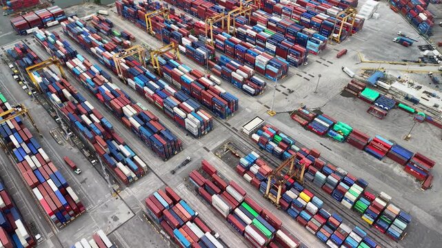Slow drone flyover above Manila Port container terminal with stacked shipping boxes, yellow gantry cranes, and service lanes showing active cargo logistics.