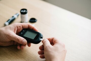 Fototapeta premium A person with diabetes using a glucometer to check their blood sugar level by inserting a test strip.