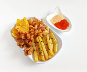Minimalist food photography of mix platter served on a white plate. The dish features crispy fried shrimp, French fries, fried crackers, and corn chips, accompanied by dipping sauces.