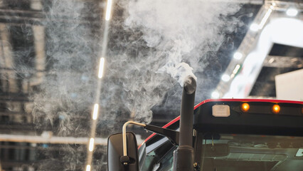 Exhaust pipe of a tractor emitting polluting smoke inside a building © Довидович Михаил