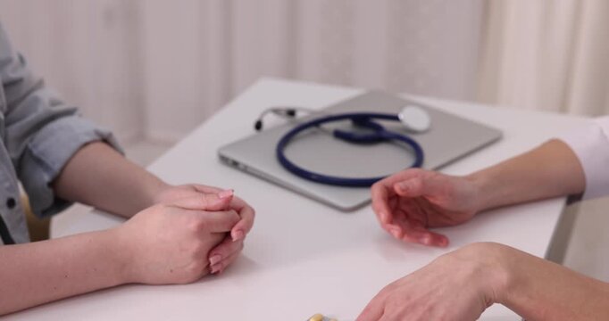 National health service (NHS). Doctor giving pills to patient at white desk indoors, closeup