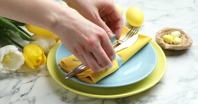 Easter celebration. Woman setting table for festive dinner on white marble background, closeup