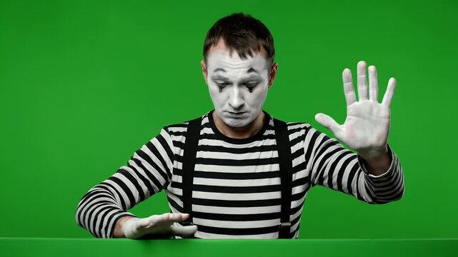 Sad mime artist trapped behind an invisible wall. Pantomime on green screen.