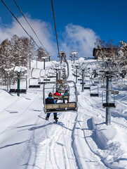 Sunny winter day with blue sky and snow-covered trees viewed from a ski lift in Japan
