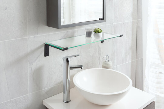 A stylish bowl-style washbasin and a mirror set against a tiled bathroom wall