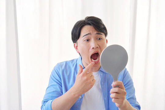 鏡を見る虫歯に悩む男性　20代