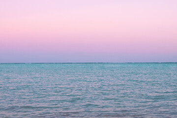 Fototapeta premium Tropical sunset with pink cloudy sky and peaceful water.