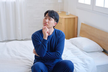 Fototapeta premium ベッドに座る20代男性 考える
