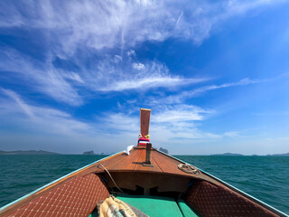 A sailing boat glides through the blue water past a historic lighthouse on the scenic coast of the island of Phuket during a summer holiday